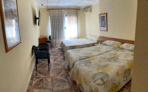 阿尔卡拉德克西韦尔特Hostal Rosaleda的酒店客房,配有两张床和椅子
