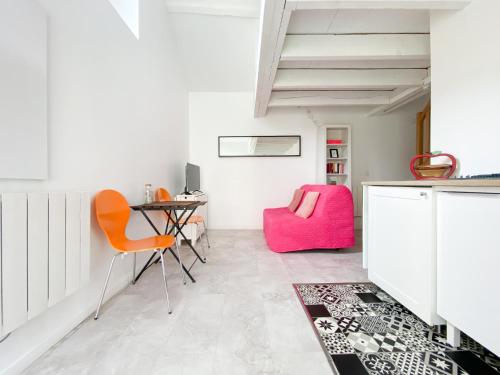 AuteuilLE COCON D'AUTEUIL - ICI CONCIERGERIE的客房配有书桌和粉红色椅子。