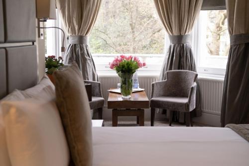 伦敦Gem Strathmore Hotel的一间卧室配有一张床和一张鲜花桌子