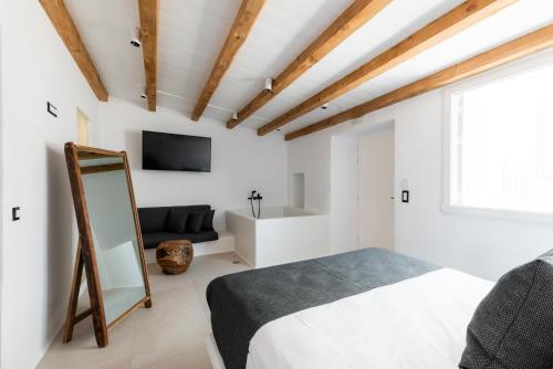 米克诺斯城Ryous Mykonos的一间卧室配有一张床、一台电视和一面镜子