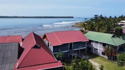 LagudriYuni Surf House的享有红色屋顶房屋和海洋的空中景致