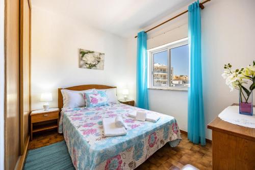 布尔高Villas Brites nº4的一间卧室配有一张带蓝色窗帘的床和一扇窗户
