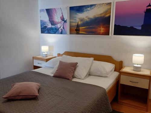 克罗诺维察Apartments Marion Klenovica的一间卧室配有一张带两盏灯的床,墙上挂有图片