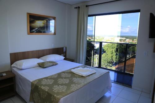 库尔韦卢Pontal Executive Hotel的一间卧室设有一张床和一个大窗户