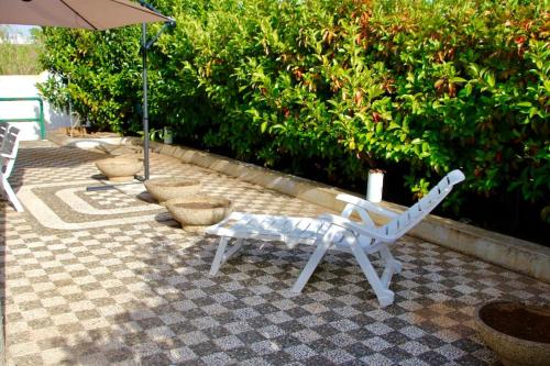 贝瓦尼亚圣彼得Villa Giovanna的庭院里的白色长凳和遮阳伞