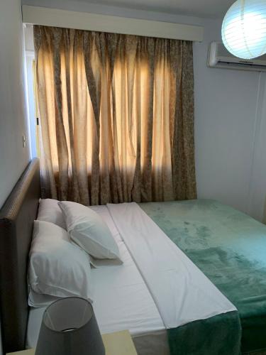 拉纳卡Green Nondas Hill的一张带枕头的床和一个带窗帘的窗户