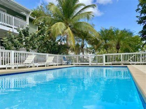 克里斯琴斯特德Breezy Nights St. Croix的一个带白色围栏和棕榈树的游泳池