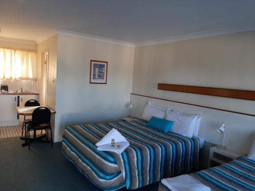 华威乡村玫瑰沃里克汽车旅馆的酒店客房设有两张床和一张桌子。