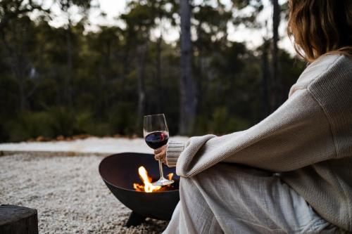 邓斯伯勒比娜玛雅灵阿普休养度假村的火坑旁拿着一杯葡萄酒的女人