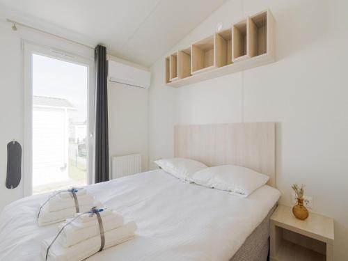 米德尔克尔克Modern mobile home in Middelkerke with garden的白色的卧室设有一张大床和一个窗户