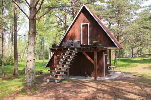 SīkragsCozy Cottage的森林中带门廊和楼梯的小小屋