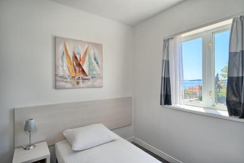 卡什泰拉Hotel Aqua - Guest Rooms & Suites Kaštela的一间卧室设有一张床,窗户设有帆船