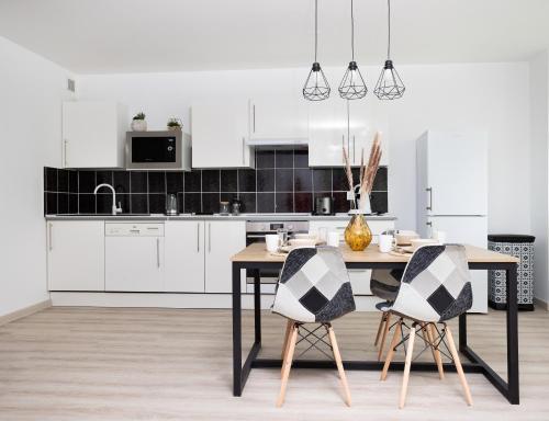 默伦LeCosyMelunais : Parking gratuit + Balcon aménagé的厨房配有白色橱柜和木桌及椅子