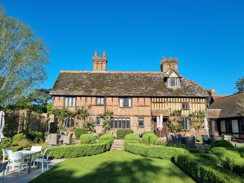 霍利Langshott Manor - Luxury Hotel Gatwick的一座古老的石头房子,前面设有一个花园
