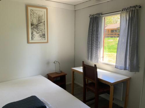 劳马Poroholman Lomakeskus的一间卧室配有一张床、一张书桌和一个窗户。