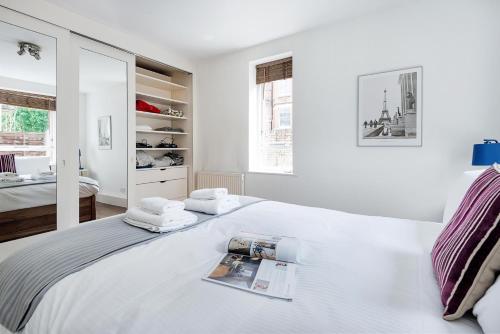 伦敦Bright and stylish apartment in trendy Islington by UnderTheDoormat的白色卧室,配有带毛巾的床