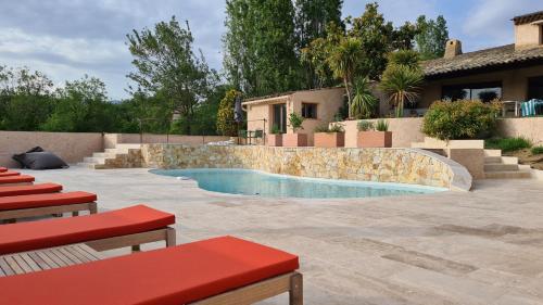 圣保罗-德旺斯Villa Martinus的一个带红色长椅和房子的院子内的游泳池
