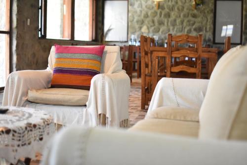 TolombónPosada de las Viñas的客厅配有两把白色椅子和五颜六色的枕头