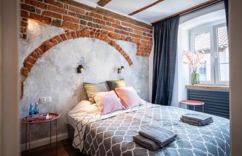 托伦Apartamenty Stare Cegły的一间卧室设有砖墙和一张带两张桌子的床