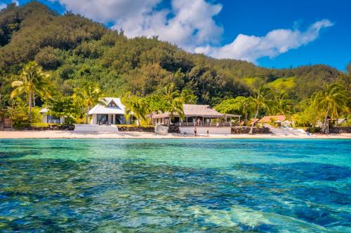 莫雷阿Moorea Island Beach Hotel的海中的一个岛屿,有房子和棕榈树