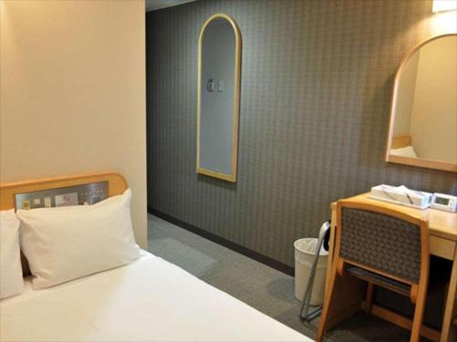 熊本县厅前绿色饭店的一间卧室配有一张床、一张书桌和一面镜子