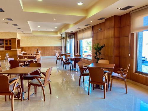 桑亨霍Duerming Areas Playa Hotel的餐厅设有木桌、椅子和窗户。