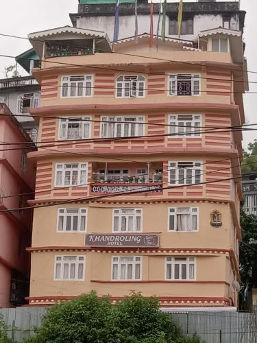 甘托克Khandroling Hotel的一座高大的橙色建筑,上面有标志