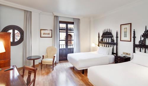 格拉纳达Sercotel Palacio de los Gamboa的酒店客房配有两张床和一张书桌