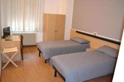BesenelloGARNI ANNA的客房设有两张床、一张桌子和一台电视。