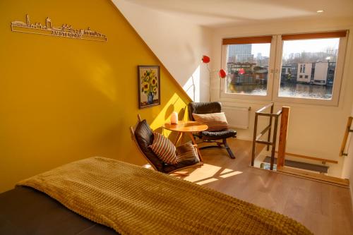 阿姆斯特丹Houseboat studio with canalview and free bikes的卧室设有黄色的墙壁和桌椅