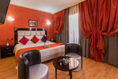 马拉喀什Hotel Meriem Marrakech的酒店客房带一张床、一张桌子和椅子