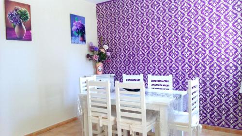 伊斯兰蒂拉Magnífico adosado de esquina con vistas al golf playas Islantilla的用餐室配有桌椅和紫色壁纸