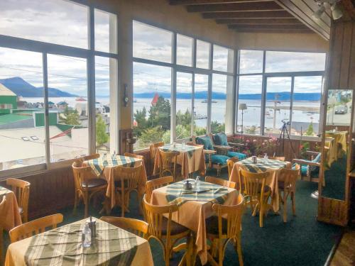 乌斯怀亚穆斯塔皮克酒店的餐厅设有桌椅和大窗户。