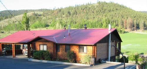 坎卢普斯Kamloops Log Home Bed and Breakfast的山上的小木屋,有红色屋顶