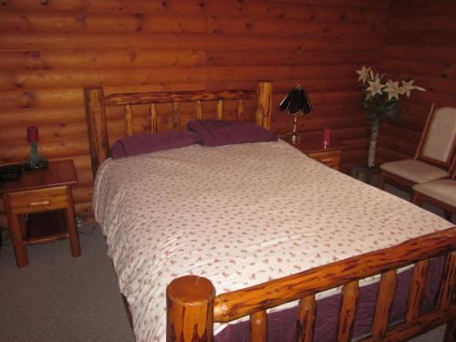 坎卢普斯Kamloops Log Home Bed and Breakfast的小屋内一间卧室,配有一张木床