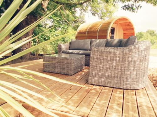 阿夫朗什Le Domaine de Pivette Chambre climatisée et insolite avec terrasse privative的木制甲板上的一张沙发和两把藤椅
