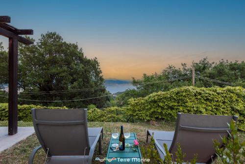 格拉齐Villa Ca Damare, TerreMarine的两把椅子和一张桌子及一瓶葡萄酒