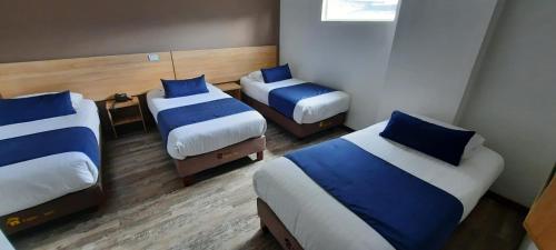 波哥大HM HOTEL Expo Inn的带3张床和蓝色枕头的客房