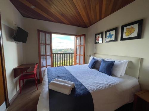 坎波斯杜若尔当Summit Suítes Hotel Campos do Jordão的一间卧室配有一张床、一张书桌和一个窗户。