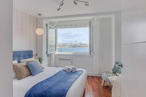 拉科鲁尼亚Riazor Ocean View Apartment的一间卧室设有一张床和一个大窗户