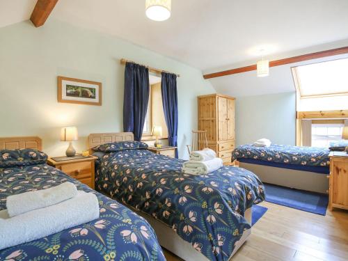 LlanegrynY Bwthyn的一间卧室设有三张床和窗户。