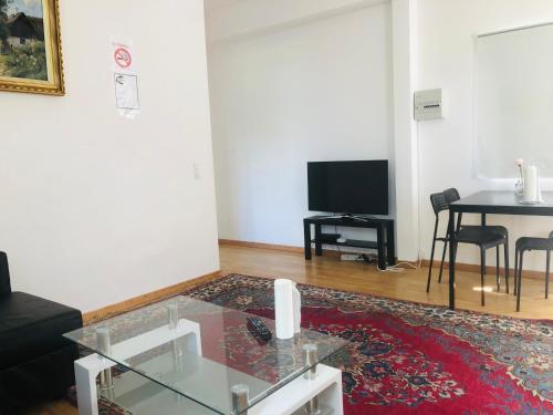 哥本哈根A1住宿公寓的客厅配有玻璃咖啡桌和电视