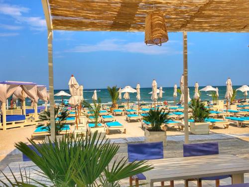 马马亚Blue Summerland Apartments的海滩上设有椅子和遮阳伞,还有大海