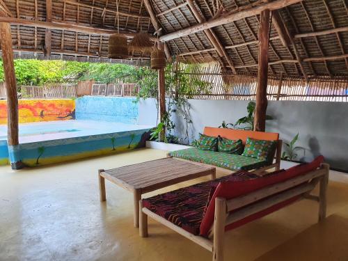 江比阿Jambiani Guest Lodge PEMBA的一间带桌子、长凳和游泳池的房间