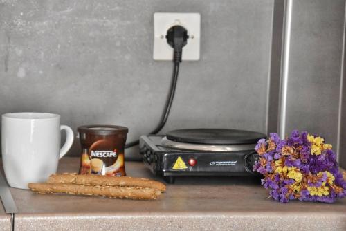 里科索翁Anemomylos Apartments的一个带烤面包机的柜台,一个杯子和鲜花