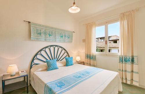 维拉西米乌斯布甘维尔公寓式酒店的一间卧室配有一张带蓝色枕头的床和一扇窗户。
