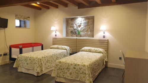 BoimortoCasa Rural Rectoral Santa Baia的一间设有两张床的客房,墙上挂着一幅画