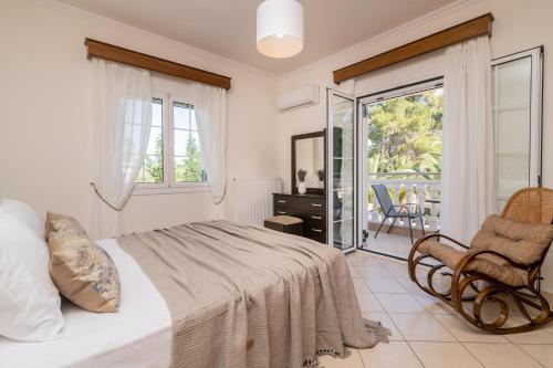 KoukounariáLuxury Villa Vanato & Pool的一间带一张床和一把椅子的卧室以及一个阳台