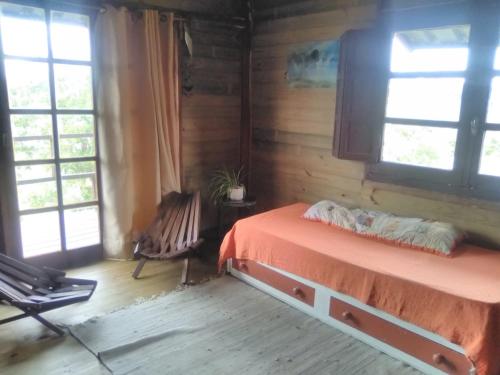 塞拉纳镇Horneritos - Cabaña en Villa Serrana的一间卧室配有一张床、一把椅子和窗户。