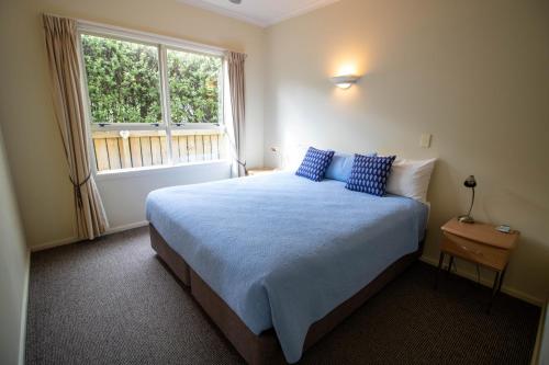 泰晤士泰晤士托斯卡纳酒店的一间卧室配有一张带蓝色枕头的床和一扇窗户。